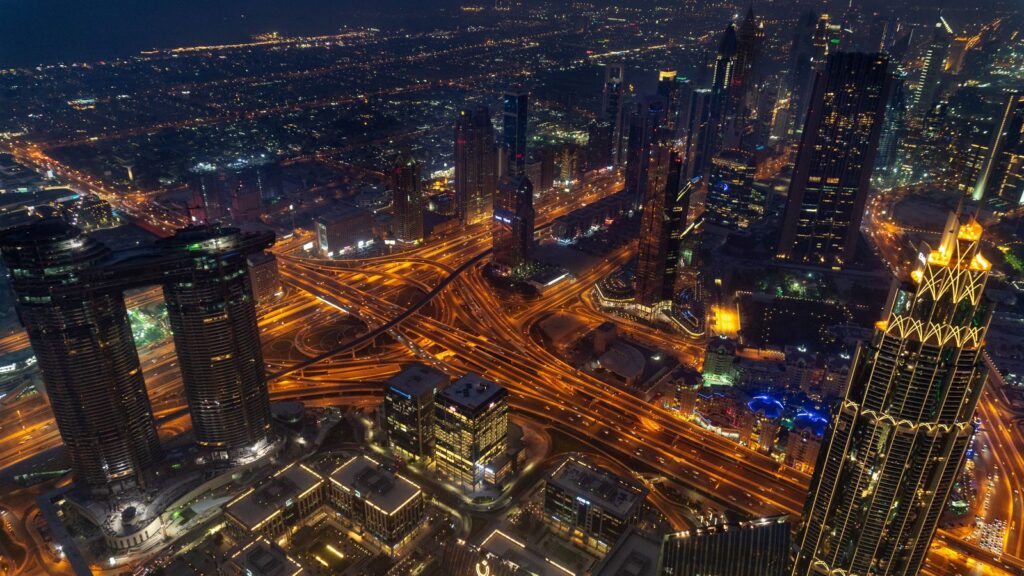 Aerial night view of a busy Dubai highway interchange lit by traffic and skyscraper lights