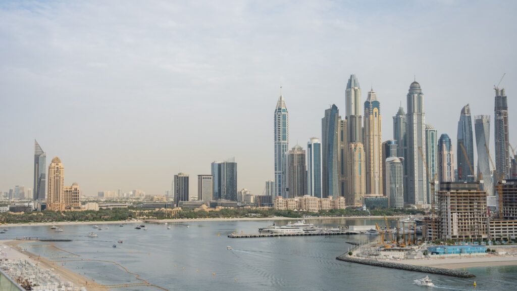 Dubai Marina skyline seen from the water on a clear day, with prominent skyscrapers including the twisted Cayan Tower