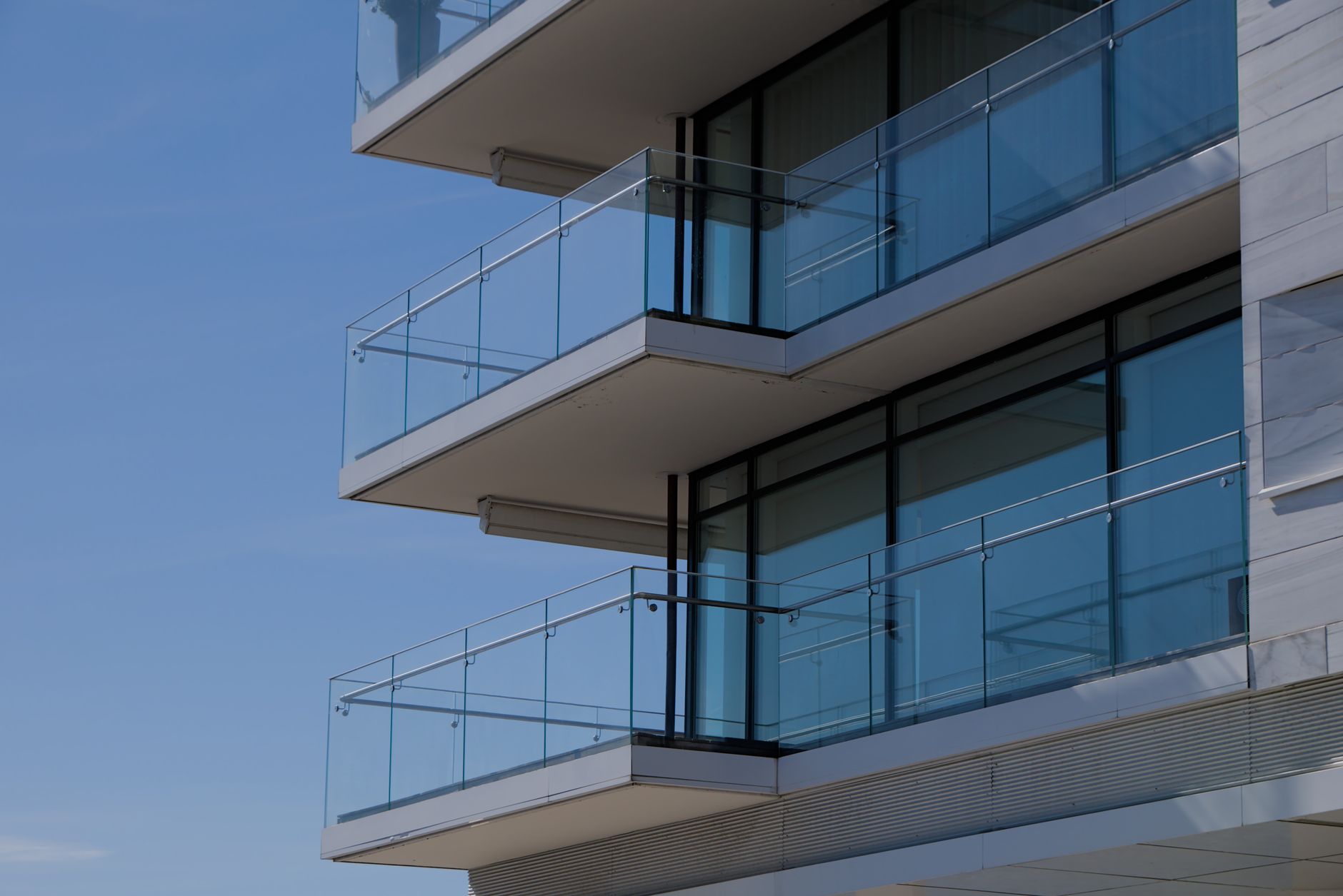 Close-up glass and balcony facade of a modern Emaar Beachfront tower against a clear blue sky