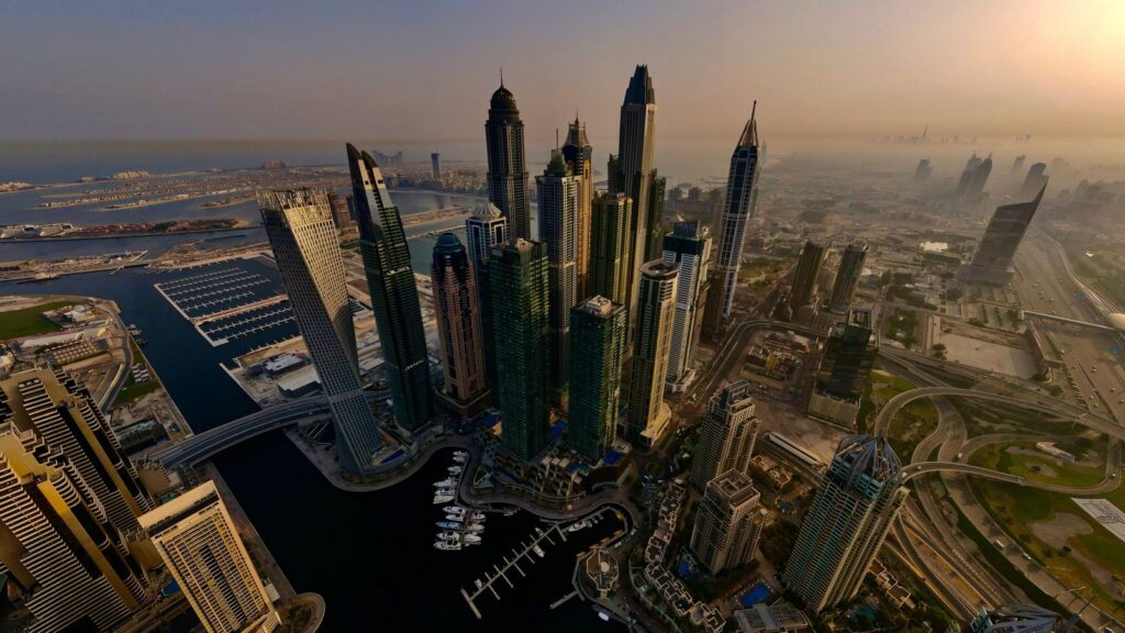 Aerial view of Dubai Marina towers and Palm Jumeirah on the coastline at sunset, representing the Dubai Marina/JBR-adjacent coastal setting near Beach Vista Tower 2 in Emaar Beachfront