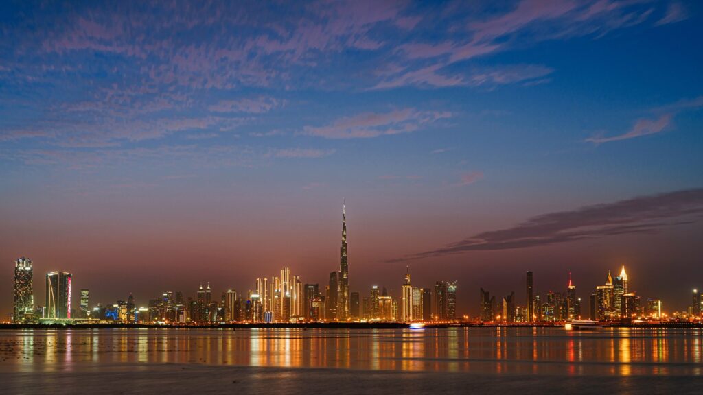 Downtown Dubai skyline at sunset with the Burj Khalifa illuminated above the waterfront
