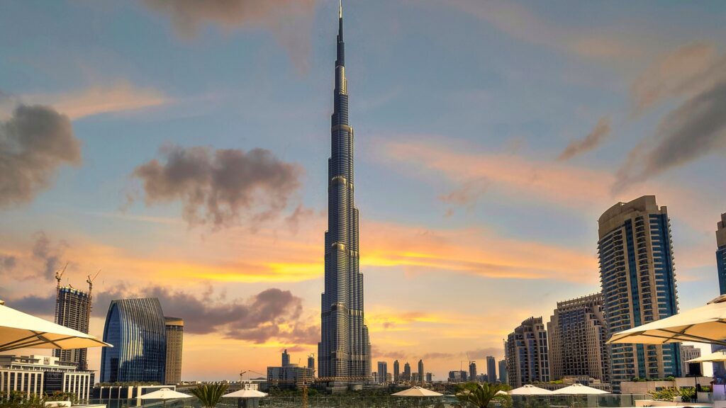 Burj Khalifa and Downtown Dubai skyline at sunset with rooftop terrace umbrellas in the foreground