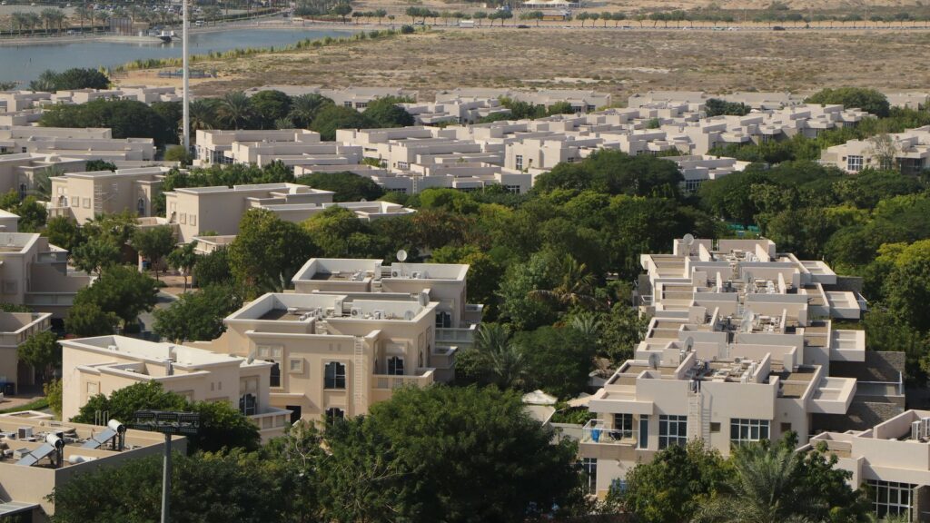 Aerial view of a low-rise villa and townhouse community in Dubai with a lagoon and dense landscaping