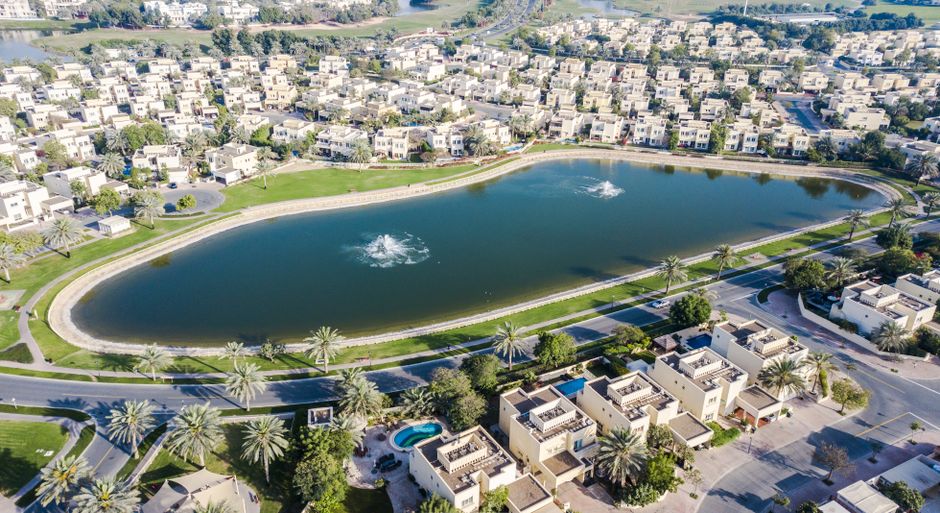 Aerial view of a Dubai villa suburb built around a tranquil lake