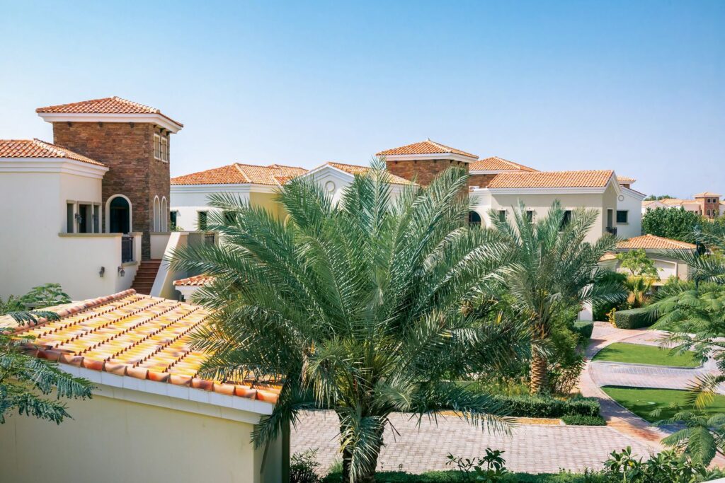 Elegant Mediterranean-style villas with red tile roofs and palm trees in Dubai, representative of DAMAC Hills 2's themed sub-communities