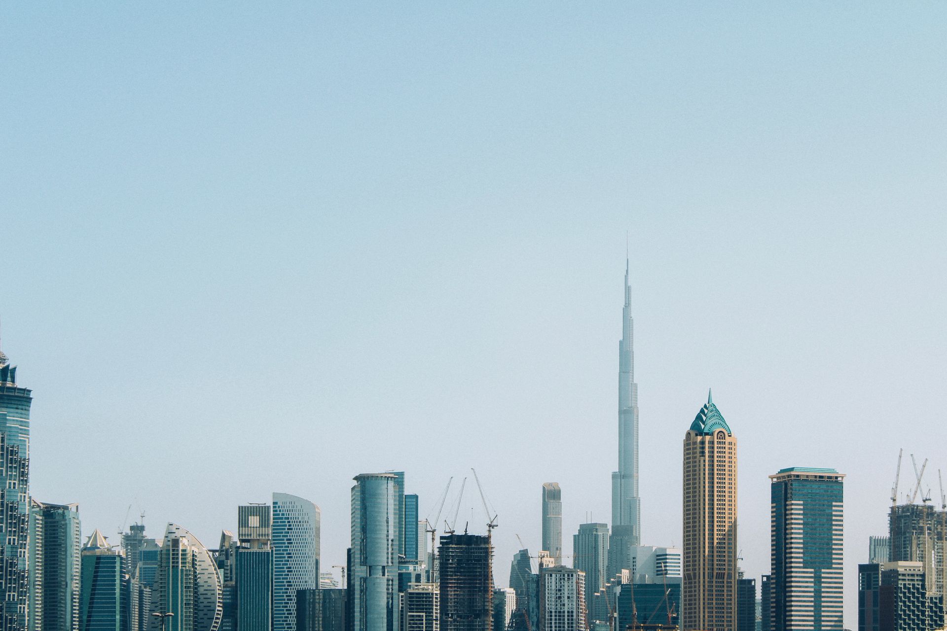 Dubai's Downtown skyline in daytime haze, with the Burj Khalifa rising above surrounding towers