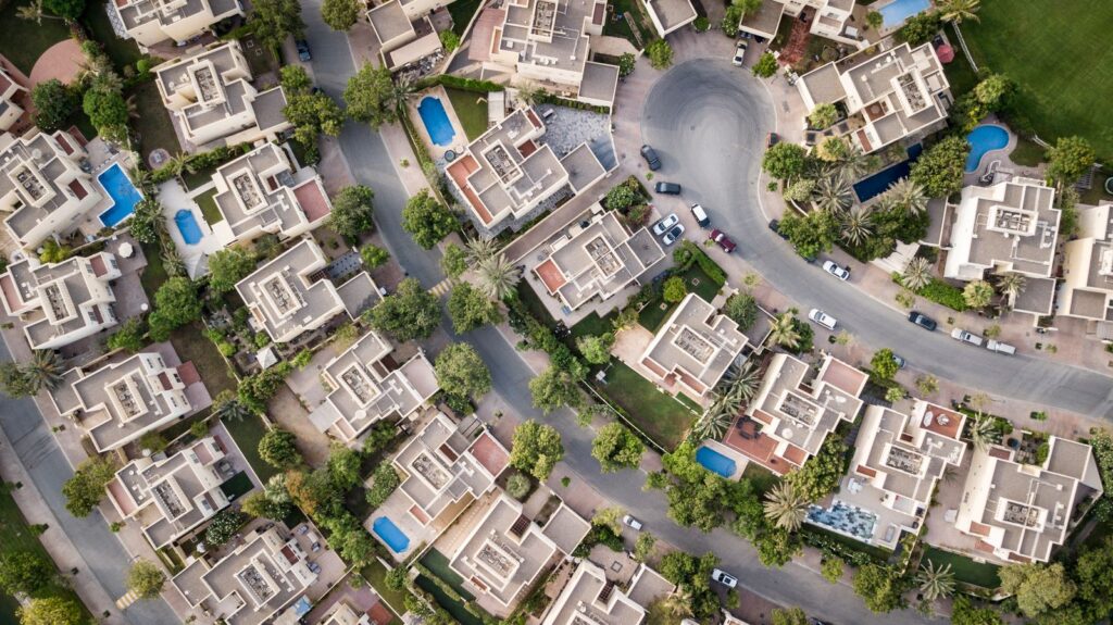 Aerial view of modern mid-rise residential buildings with pools in Dubai, representative of Dubai Sports City's Canal Residence district