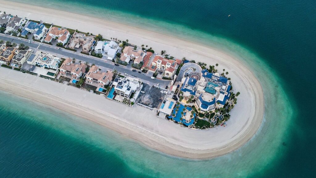 Aerial view of a Palm Jumeirah frond tip with waterfront residences and turquoise water, representing the palm-island waterfront setting of Palm Jumeirah, Dubai