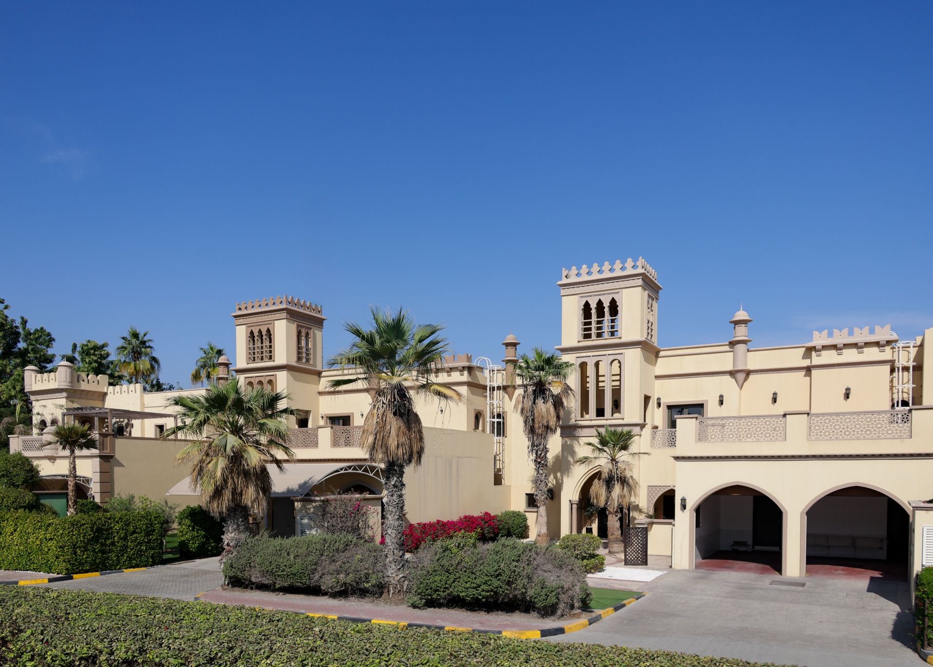 Cream Arabic-Mediterranean villa exterior with corner towers and palm landscaping, Palm Jumeirah, Dubai
