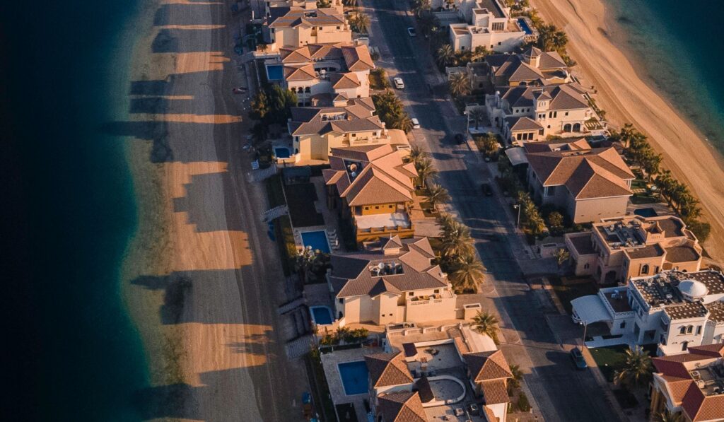 Aerial view of Palm Jumeirah frond villas with terracotta roofs and private pools at sunset, Dubai