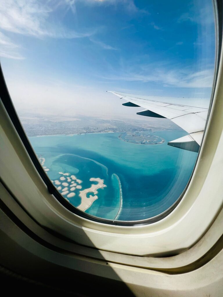 Aerial view through an airplane window of Palm Jumeirah island and the World Islands, Dubai
