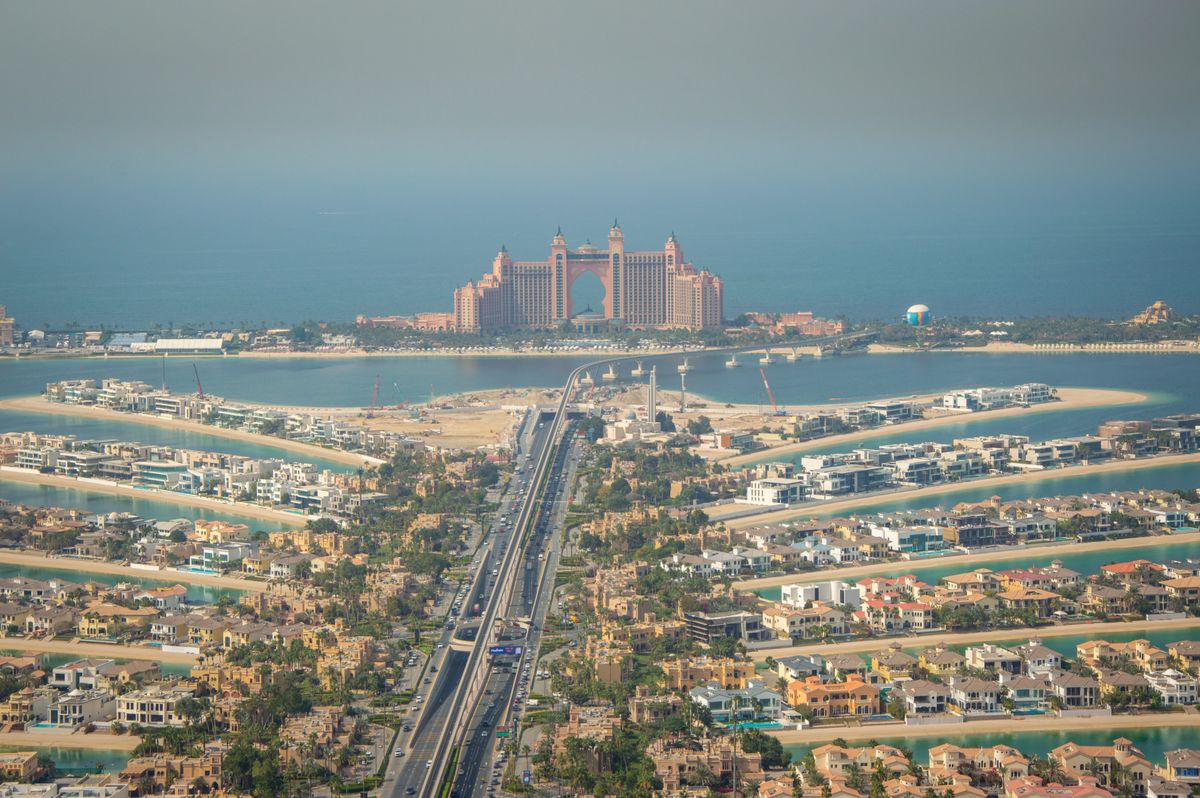 Aerial view down Palm Jumeirah's trunk road toward frond villa communities, Dubai