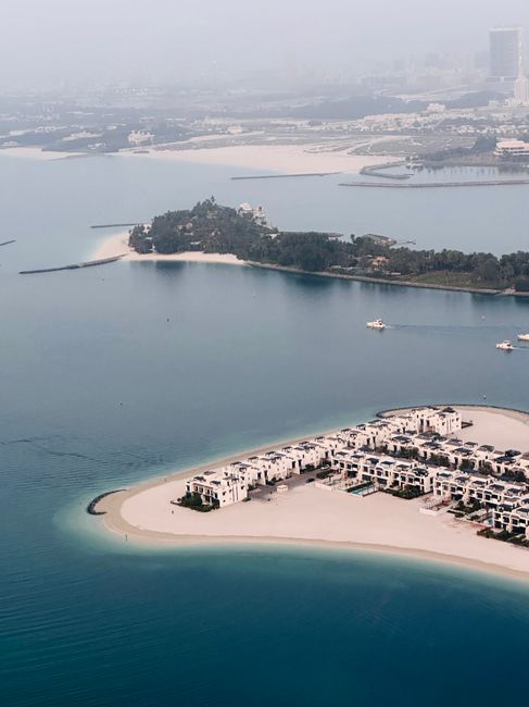 Aerial view of a crescent-shaped Palm Jumeirah frond with beachfront villas, Dubai