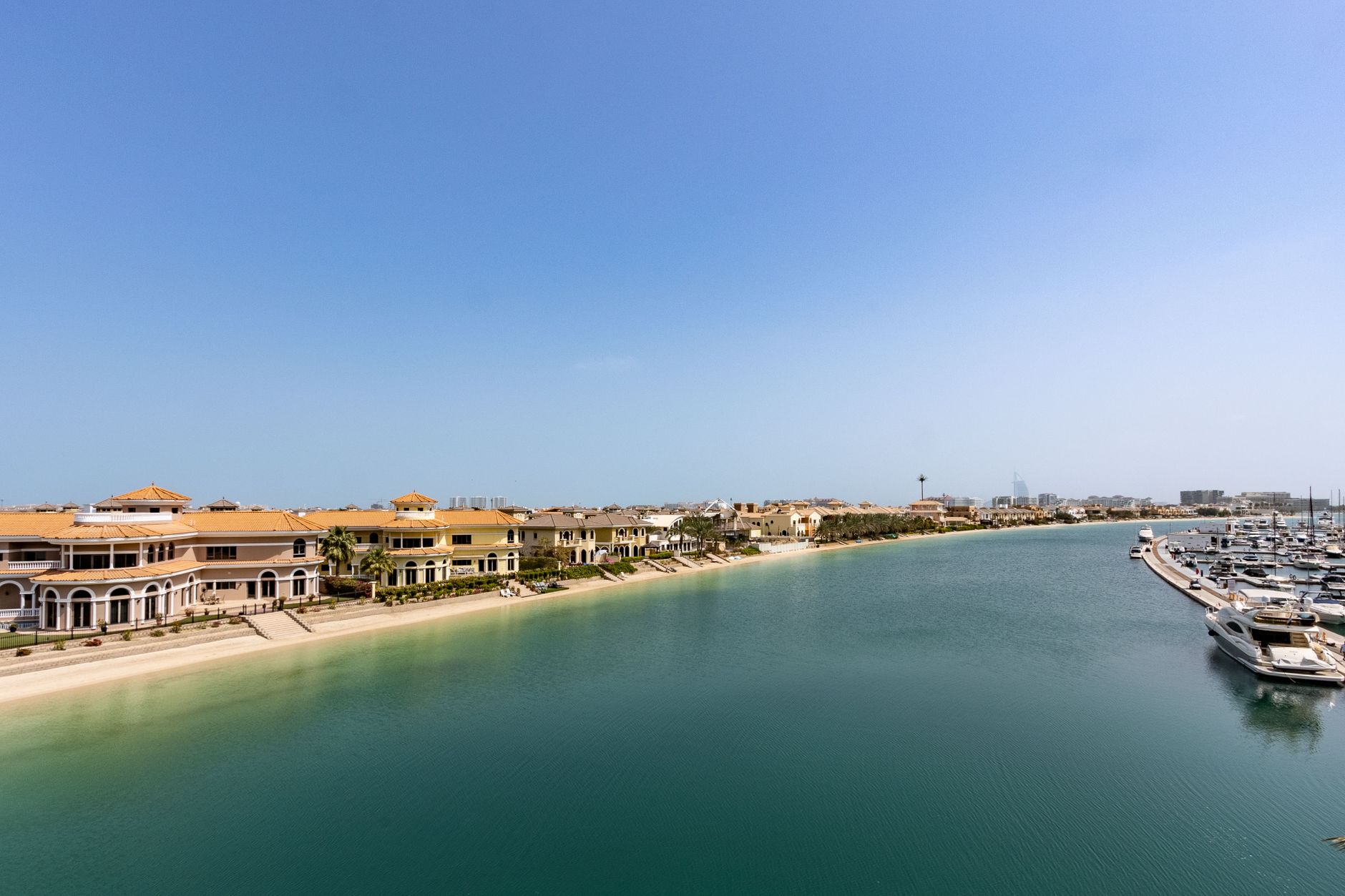 Aerial view of Palm Jumeirah waterfront with villa fronds and marina basin, Dubai