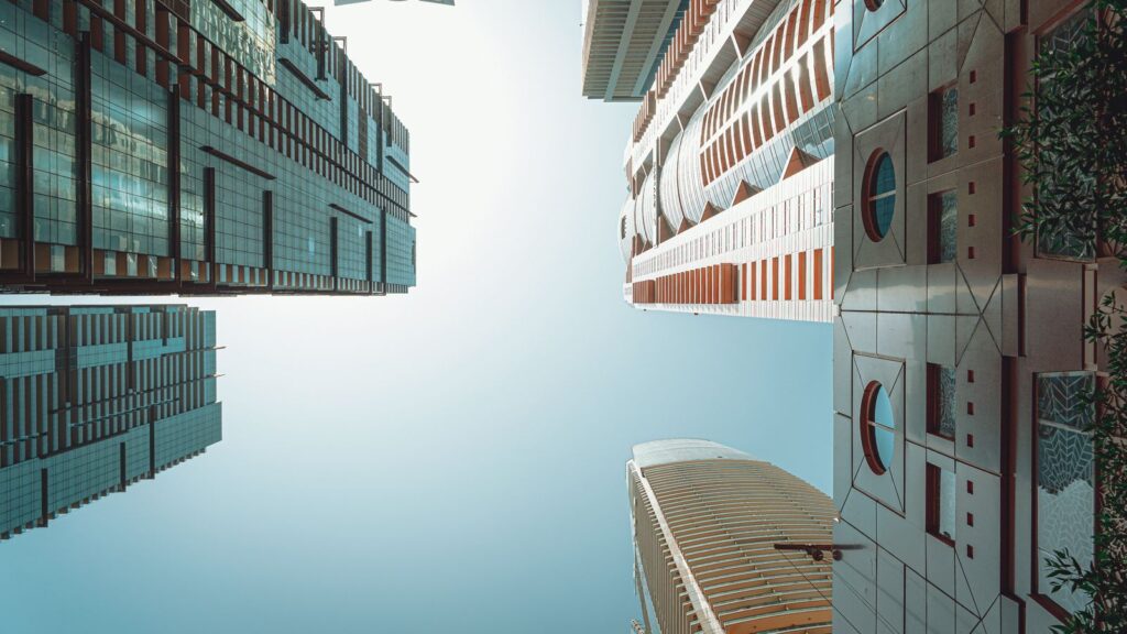 Low-angle view of modern glass and concrete high-rise towers against a clear blue sky in Dubai's DIFC financial district