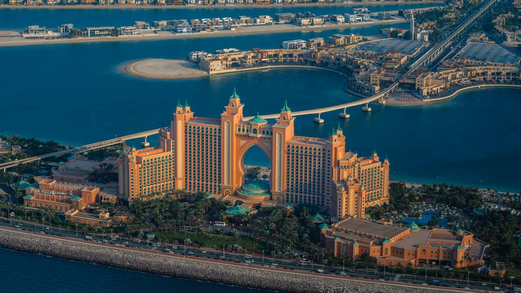 Aerial dusk view of Palm Jumeirah's trunk and fronds with Atlantis The Palm hotel and the mainland bridge, no people visible