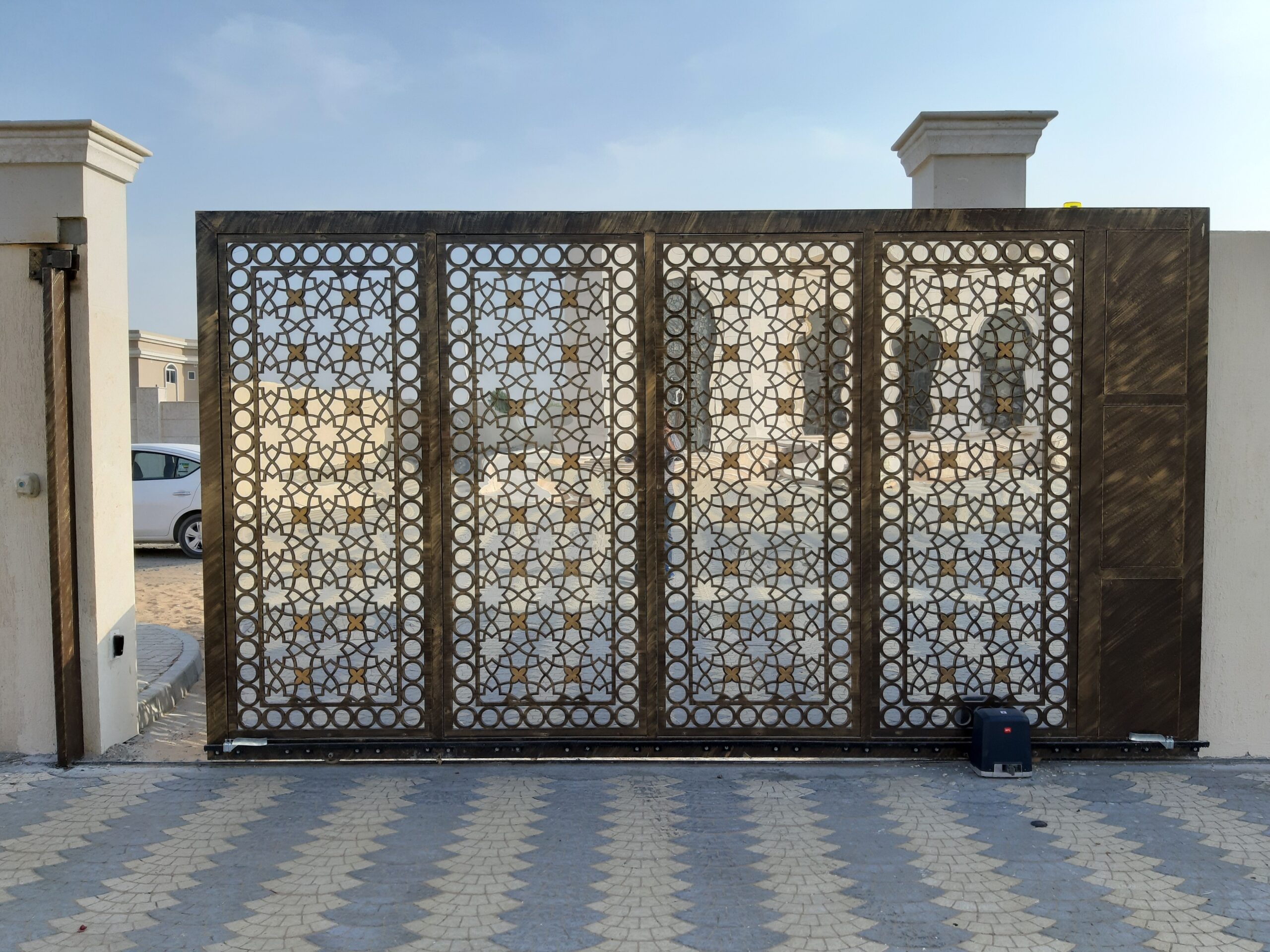 Ornate bronze and gold gated villa-compound entrance with geometric Islamic-pattern cutwork, representative of 180 Degrees Villas' gated community in Liwan, Dubai