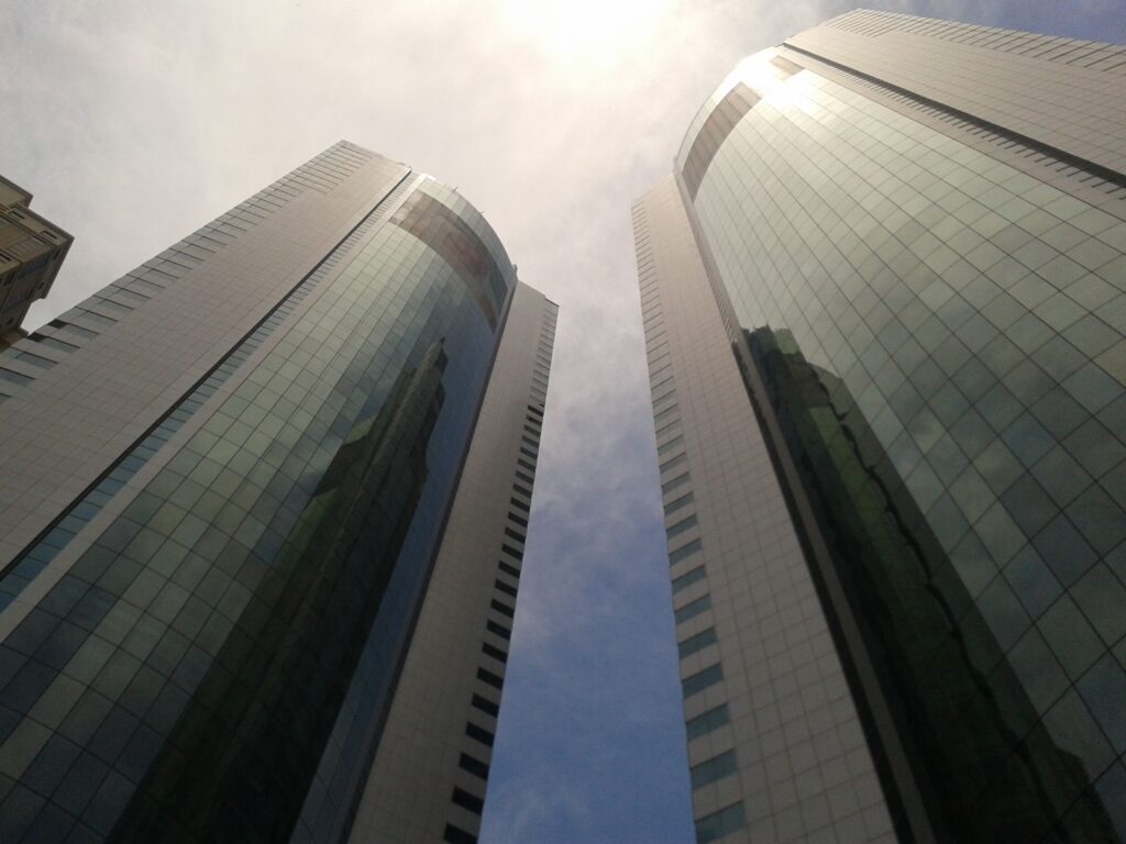 Low-angle photo of curved modern glass residential skyscrapers against a bright sky