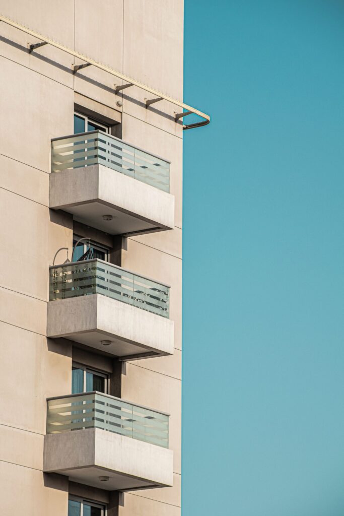 Modern cream apartment building exterior in Dubai with glass balconies against a clear blue sky