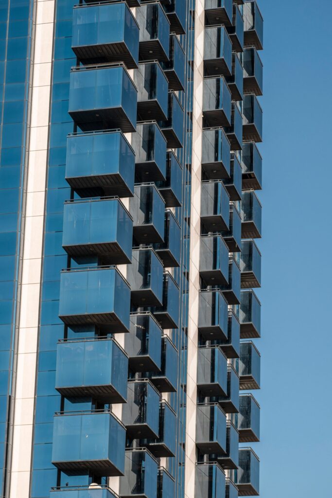 Sunlit blue glass balconies stacked on the facade of a modern high-rise tower in Dubai