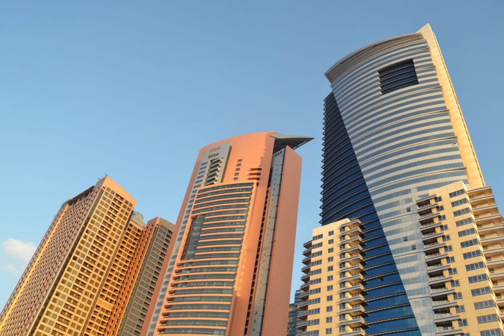 Low-angle daytime view of two Dubai high-rise towers against a clear sky