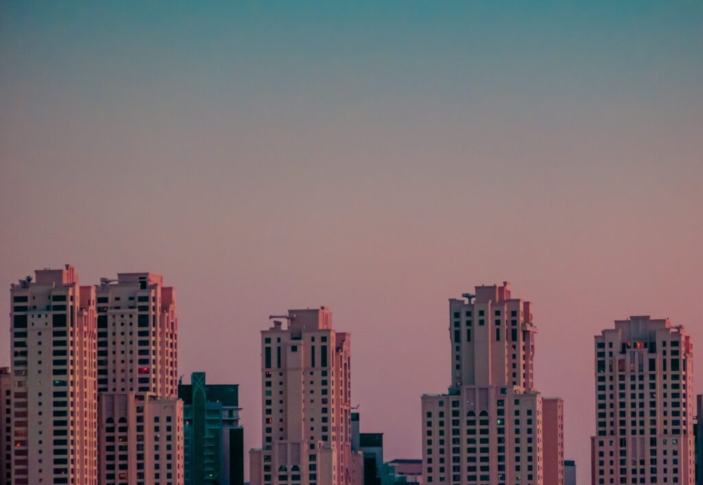 Pink to teal dusk sky over a row of mid to high-rise residential apartment towers in Dubai