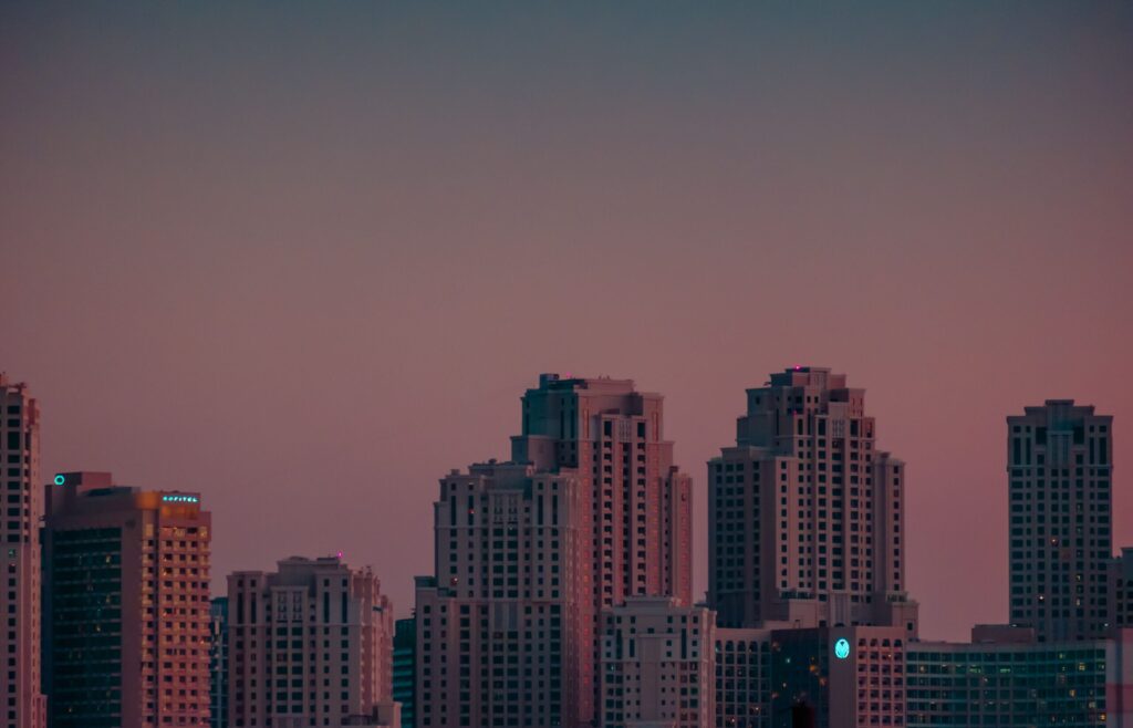 Dusk skyline of Business Bay-style residential towers in Dubai against a pink-to-blue gradient sky