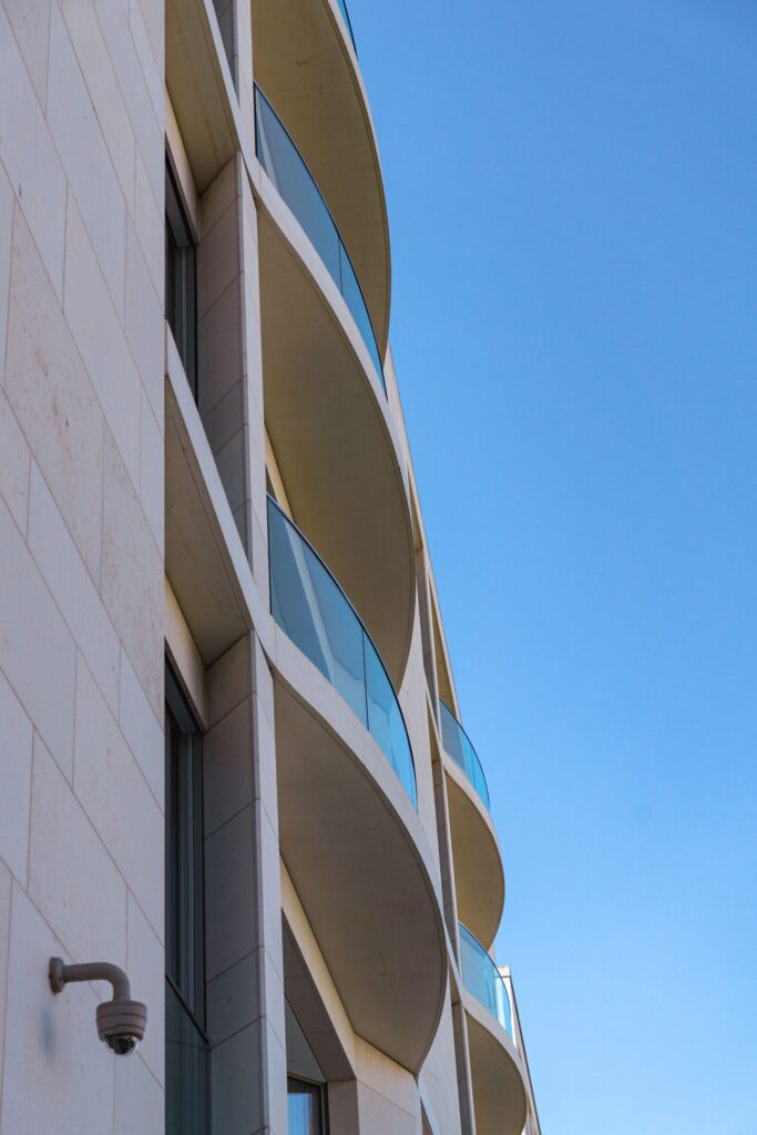 Low angle view of a curved balcony apartment building against a clear blue sky