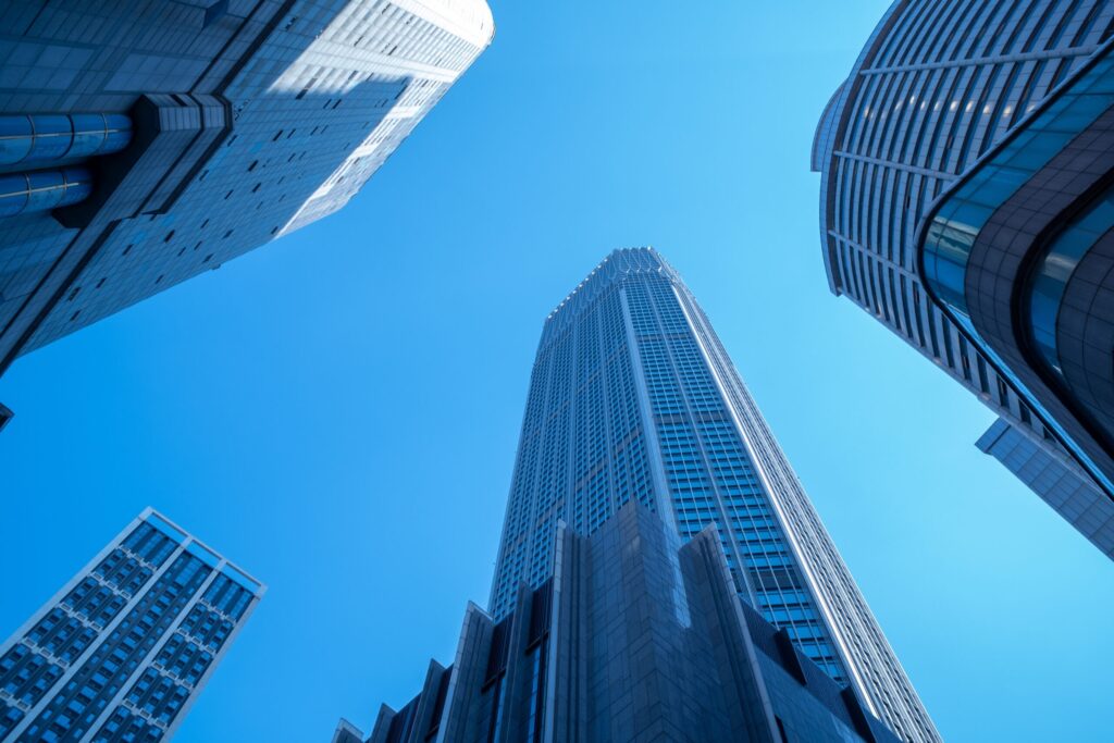 Low angle view of modern skyscrapers against a bright blue sky, showcasing urban architecture
