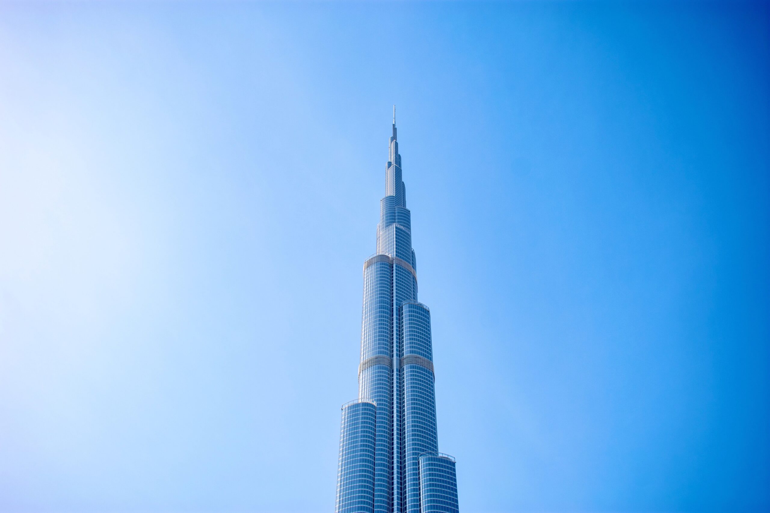 Close-up upward crop of the Burj Khalifa's tapering spire against a clear blue sky, representative of Downtown Mada Residences by Yanjoon, Burj Khalifa District, Downtown Dubai