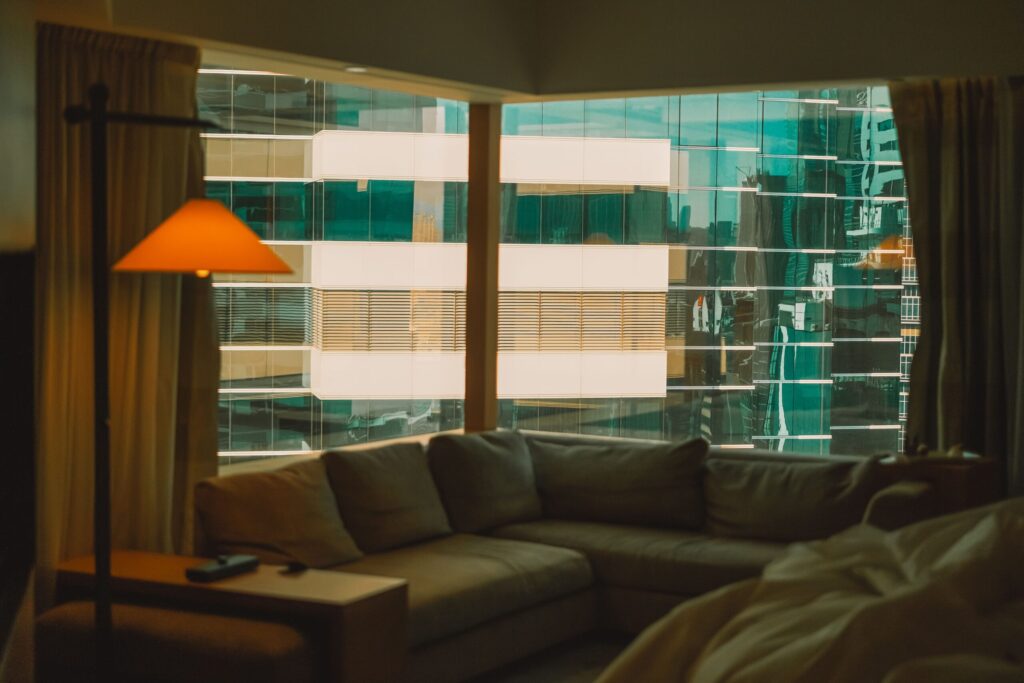 Interior corner living room with floor-to-ceiling windows showing a glass-facade skyline view