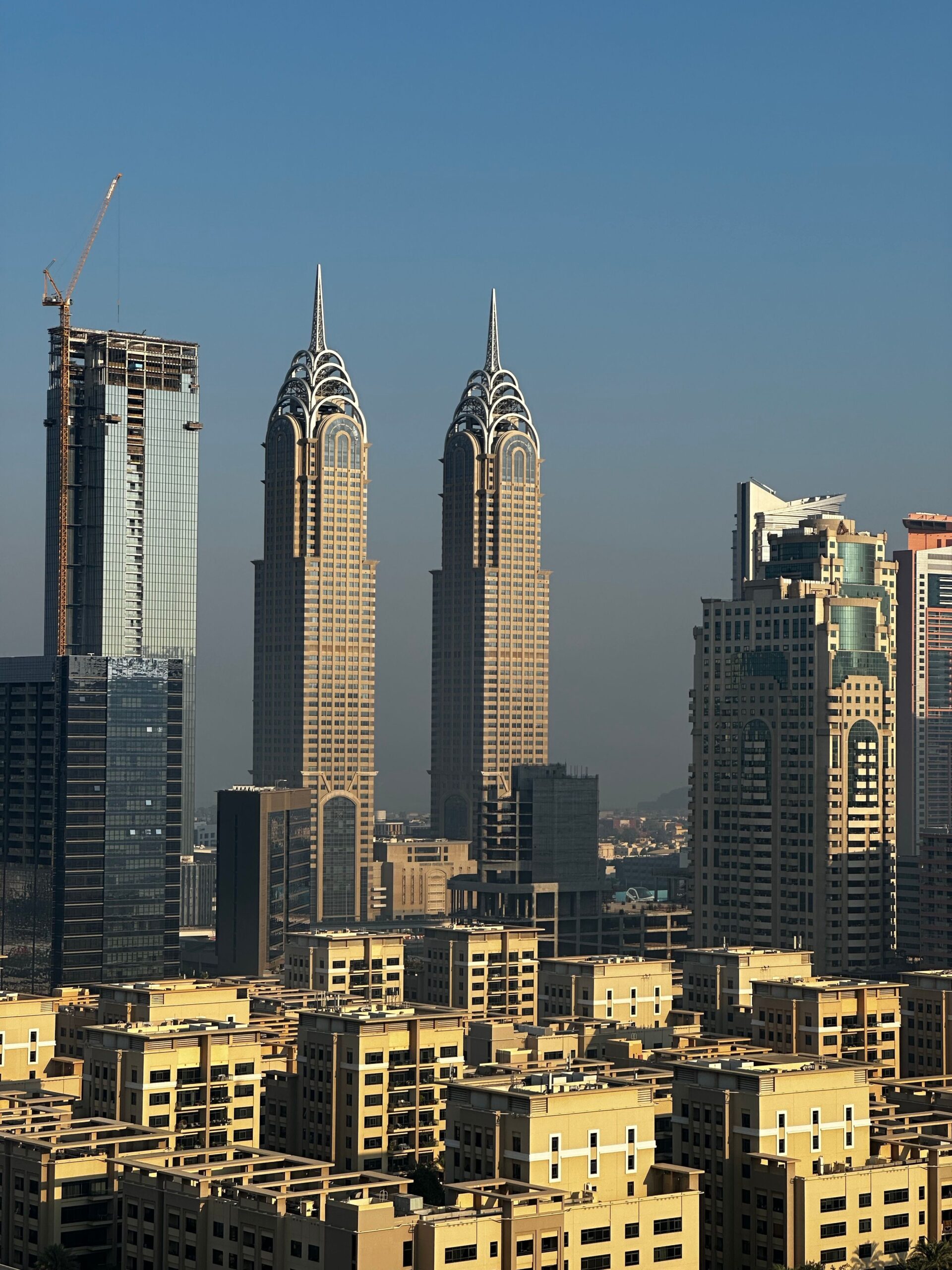 Dubai high-rise towers with an under-construction building in the foreground, representative of the Business Bay skyline near Executive Towers.