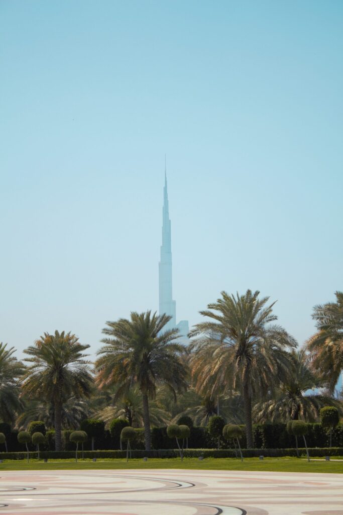 Burj Khalifa spire rising above mature date palms against a clear blue sky, near The Residences 7, Old Town Island, Downtown Dubai