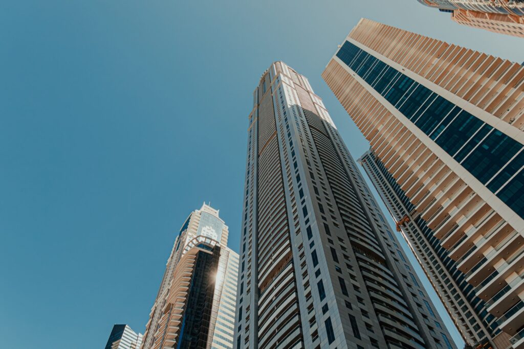 Modern glass and stone high-rise towers against a vivid blue sky in Dubai