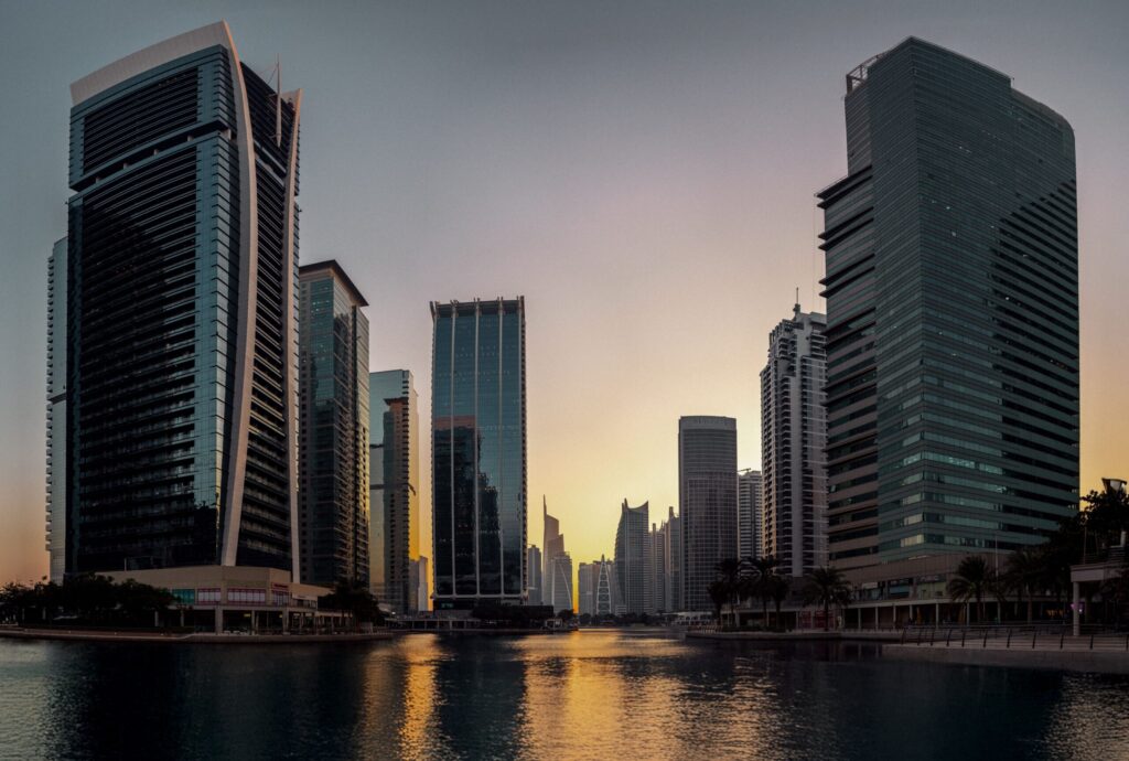 Sunset silhouette of a Dubai Marina tower cluster reflecting over calm water