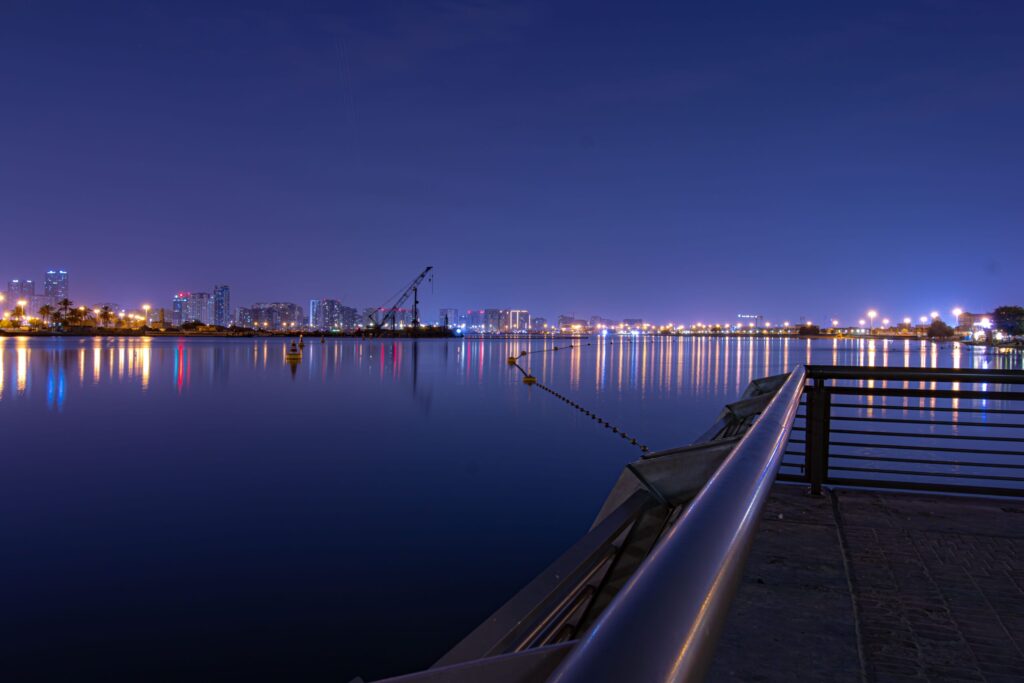 Night waterfront cityscape with calm dark water and reflected city lights