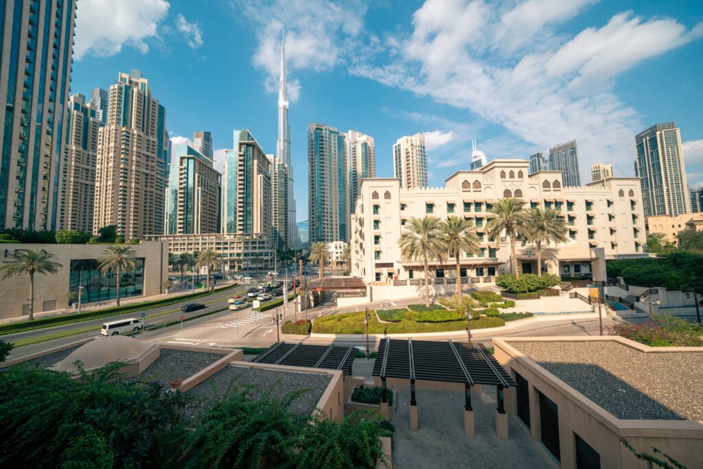 Downtown Dubai skyline with Burj Khalifa rising behind a low-rise Arabian-style building under a clear blue sky