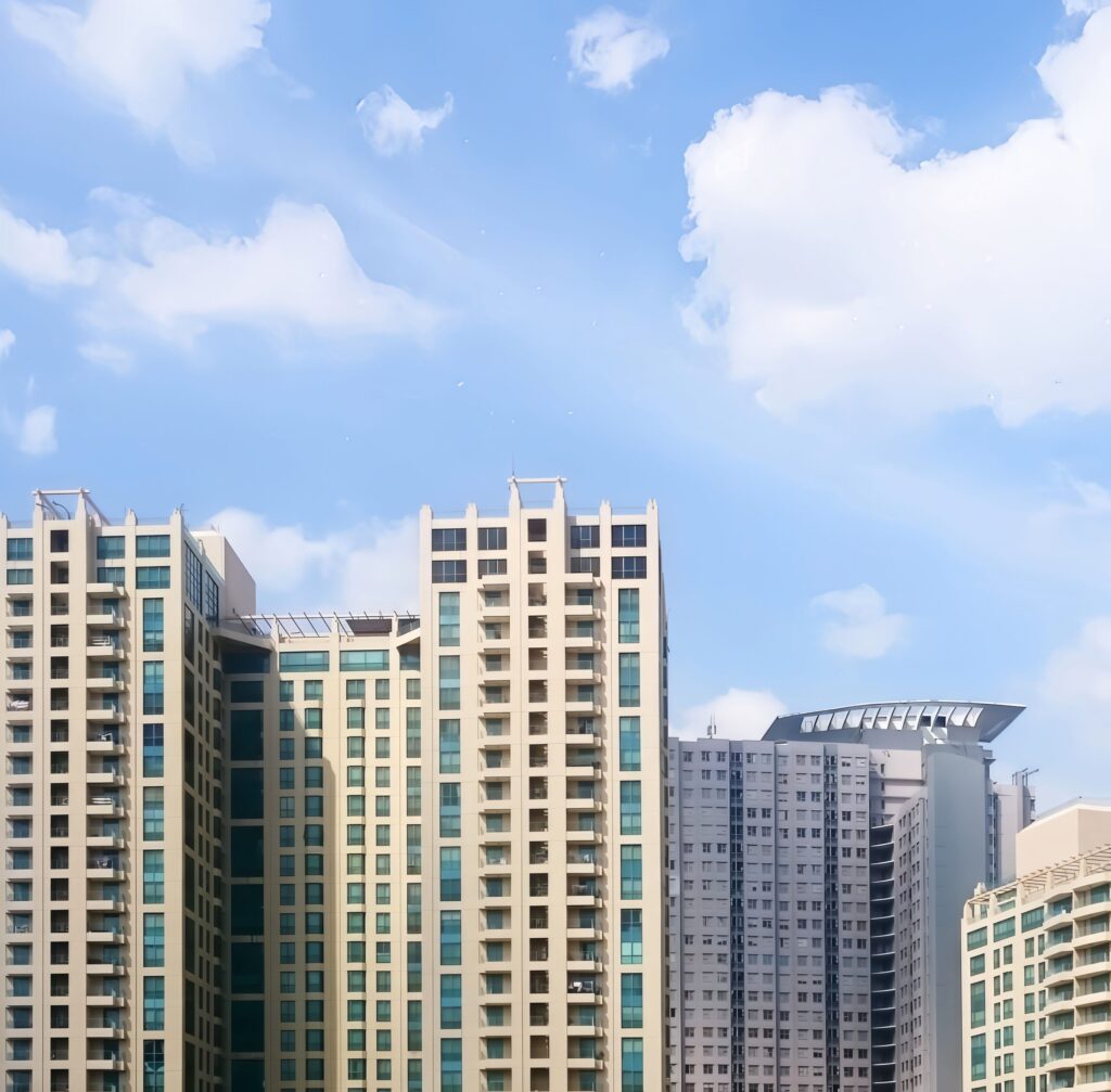 Cream and grey high-rise apartment towers with balconies against a clear blue sky in Dubai Marina
