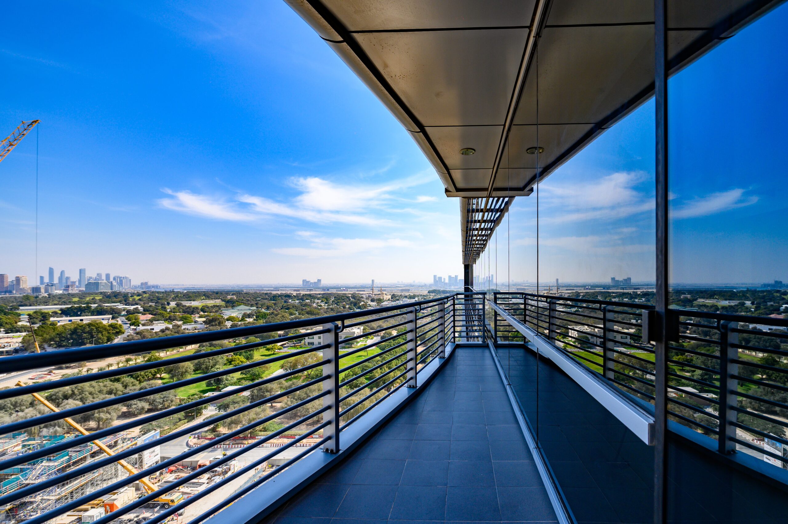 High-rise balcony corridor overlooking the Dubai skyline, glass balustrade