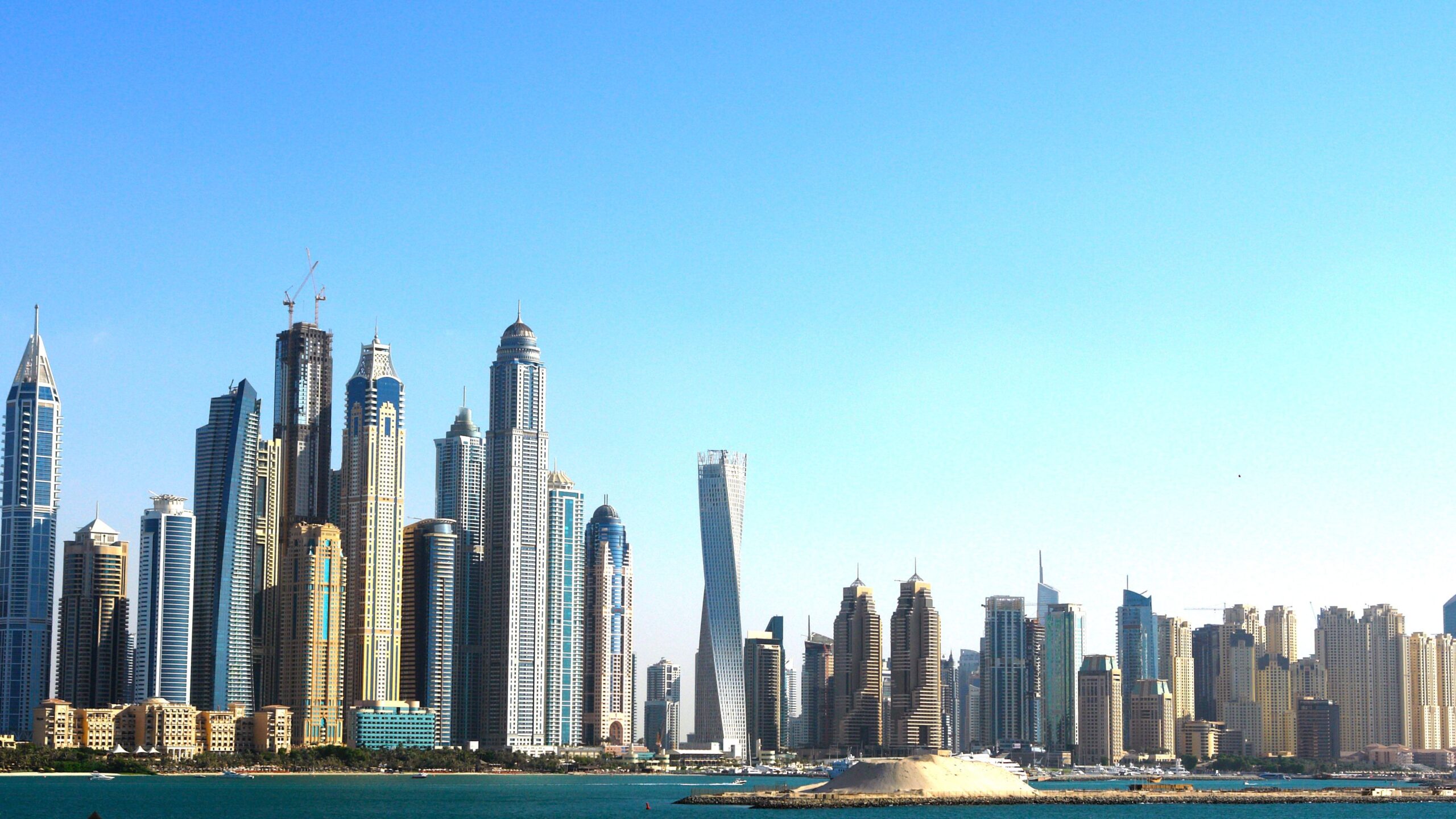 Modern high-rise residential towers along Dubai's waterfront skyline under a clear blue sky