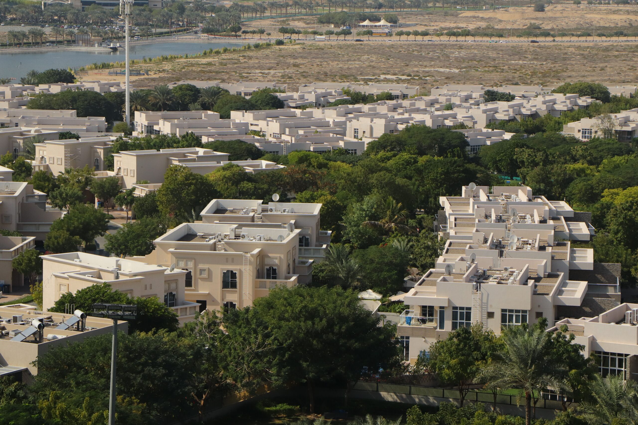 Aerial view of a Dubai villa community with sand-toned low-rise villas and dense greenery, representative of the Reem villa-community landscape near Mira 4.