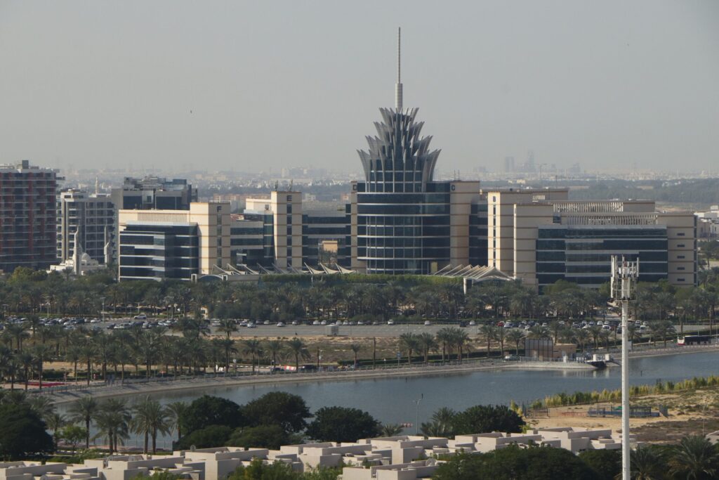Aerial view of Dubai Silicon Oasis with villa and townhouse rooftops in the foreground and the wider Dubai skyline behind, representative of Arabian Ranches' surrounding Dubailand corridor, Dubai