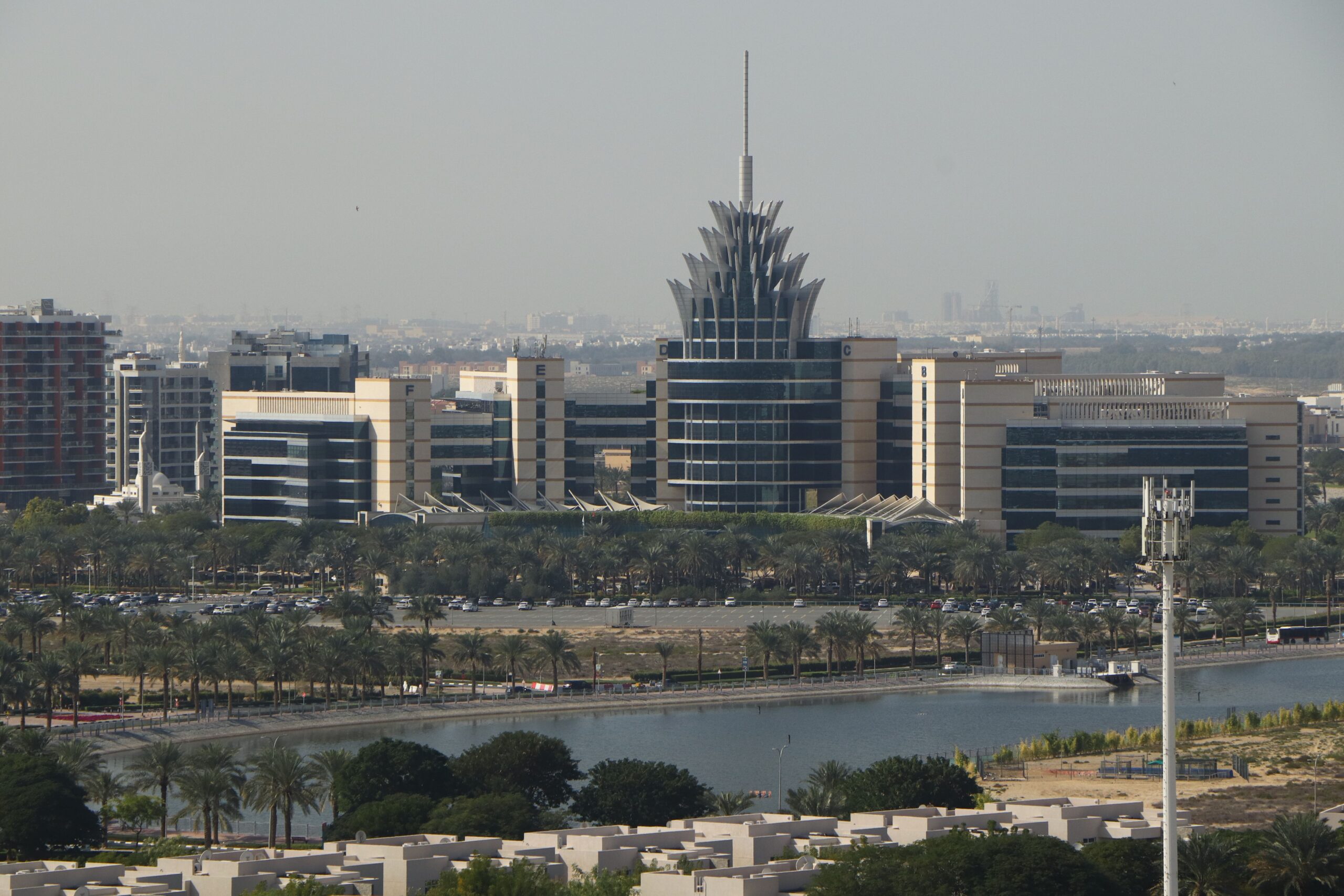 Aerial view of Dubai Silicon Oasis with villa and townhouse rooftops in the foreground and the wider Dubai skyline behind, representative of Arabian Ranches' surrounding Dubailand corridor, Dubai