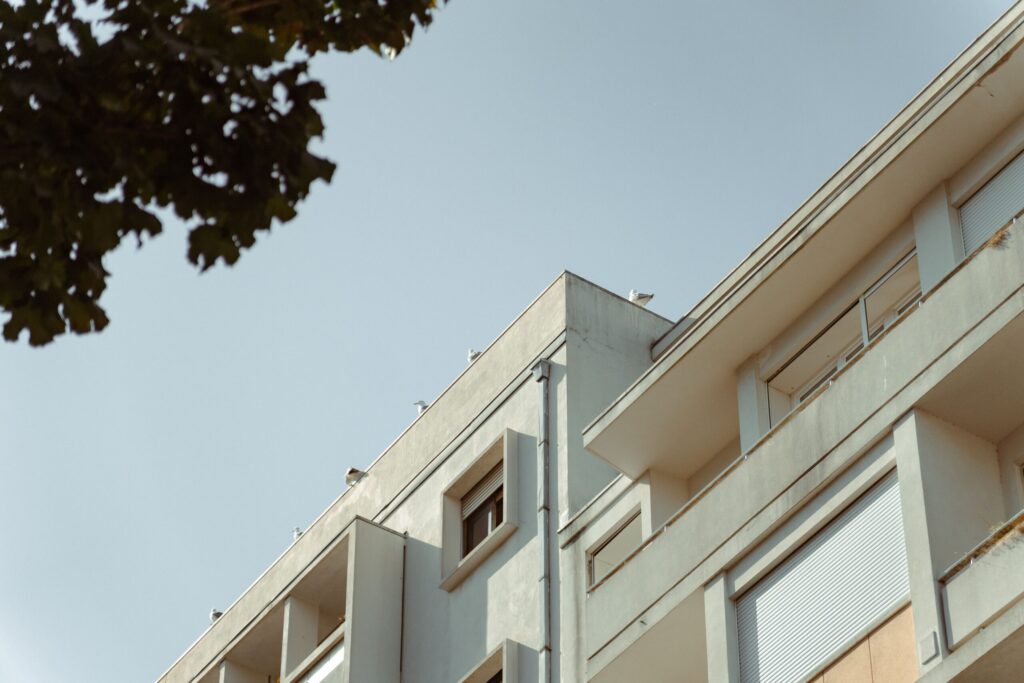 Low-angle view of a white mid-rise apartment building corner, Al Qusais, Dubai
