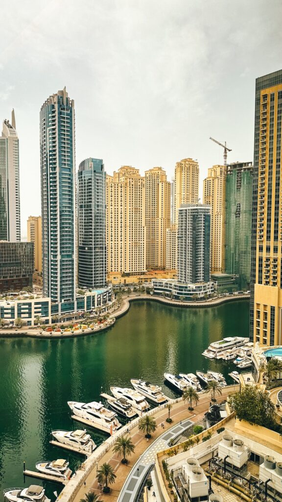 Aerial elevated view of Dubai Marina waterfront with yachts moored along the promenade and a dense high-rise skyline