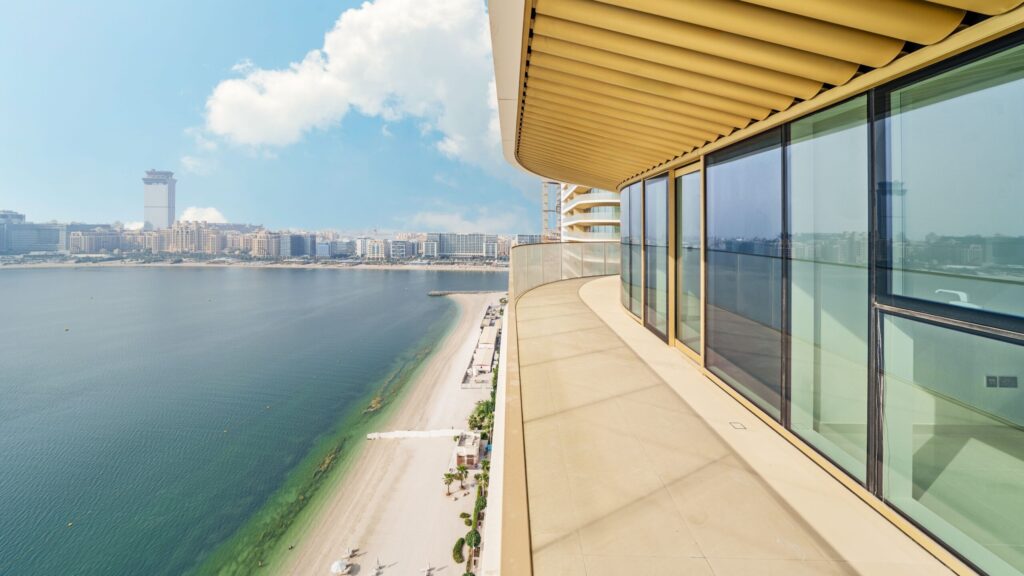 Curved balcony of a beachfront high-rise apartment overlooking Dubai's coastline and skyline