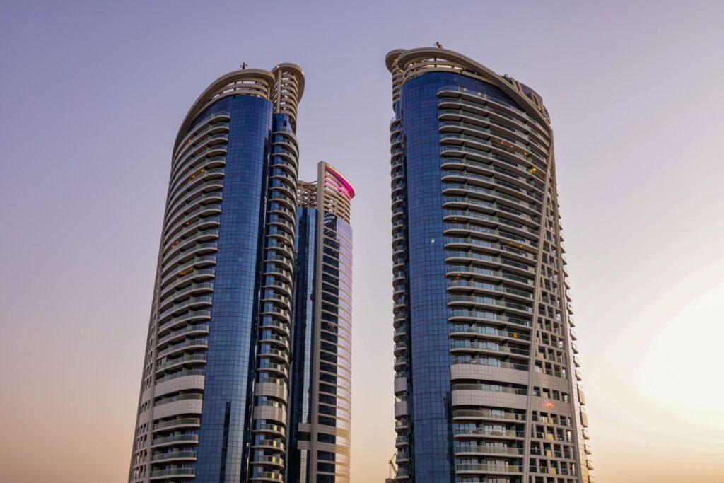 Twin curved glass residential towers at sunset near Bella Rose, Dubai Science Park
