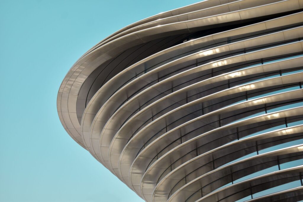 Modern steel facade against a clear blue sky, showcasing cutting-edge curved architecture