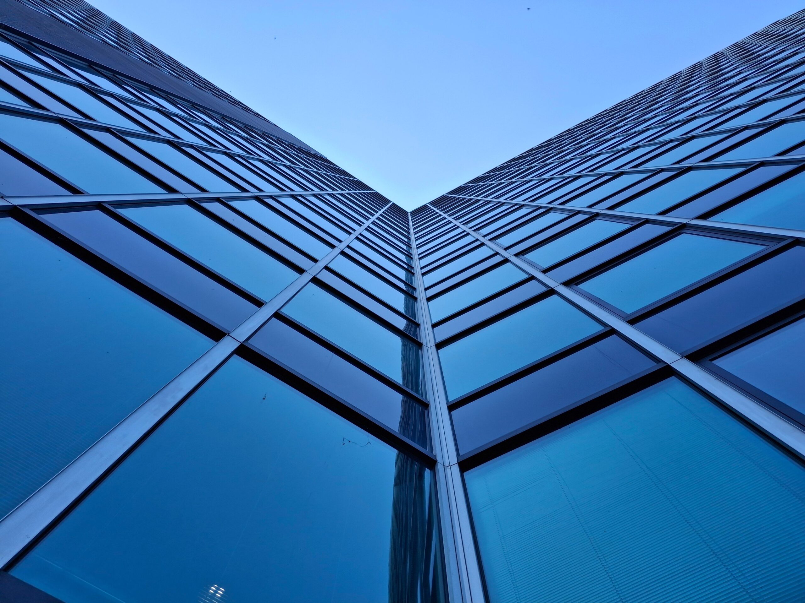 Upward-angle view of a modern blue glass Dubai skyscraper facade near Executive Tower M, Business Bay
