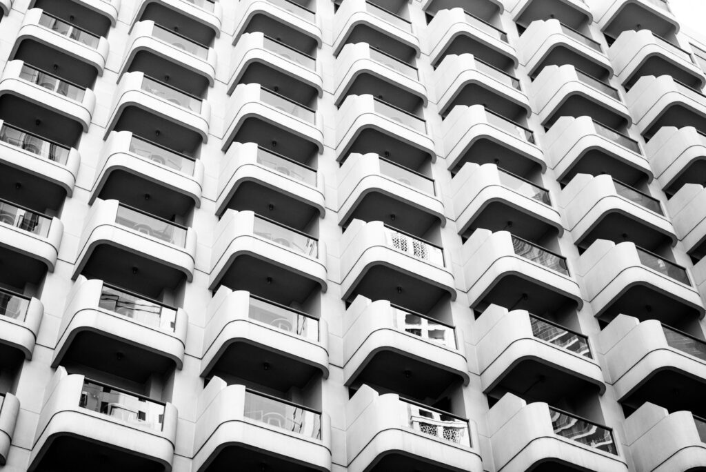 Black and white low-angle view of a modern high-rise with a repeating scalloped balcony facade